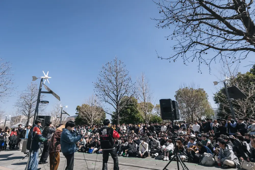 青空の下で座って見る観客とストリートステージ
